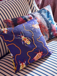 three decorative pillows sitting on top of a striped couch