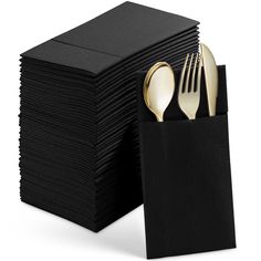 a stack of black napkins with gold forks and spoons in front of it