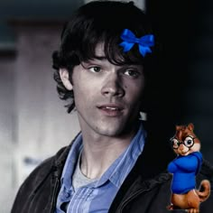 a man with a blue bow on his head holding a small toy squirrel in his hand