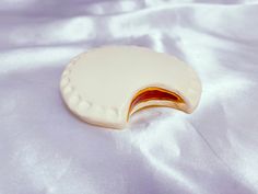 a cookie shaped like an egg on a white satin surface with red and yellow decoration