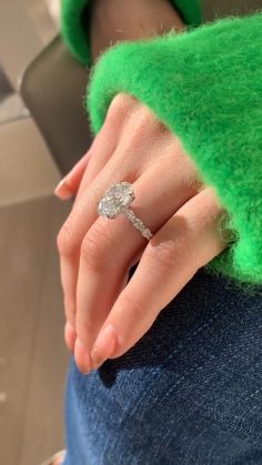 a woman's hand with a diamond ring on her left wrist and green sweater