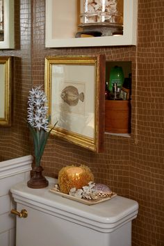 there is a vase with flowers on the shelf next to the toilet in the bathroom