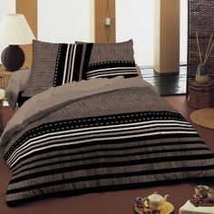 a bed with black and white striped comforter next to a lamp on the floor