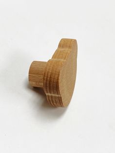 a wooden knob on a white surface with one end turned to look like it is holding something