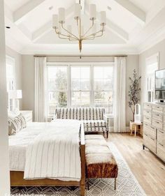 a bedroom with a bed, dresser and window in the middle of it that has white curtains on both sides