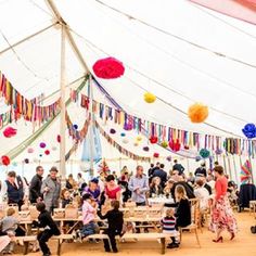 a group of people sitting around tables under a tent