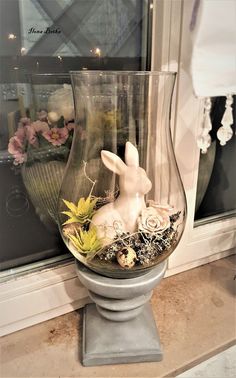 a glass vase filled with flowers and a white bunny sitting on top of it's side