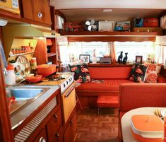 the kitchen and living area of an rv with orange accents, wood flooring and cabinets