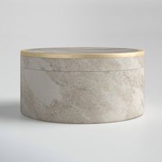 a round white marble box with gold trim on the top and bottom, sitting in front of a gray background