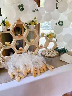 a dessert table with cupcakes, cookies and other treats on it in front of balloons