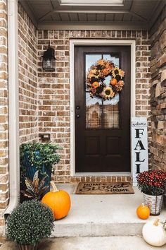 a front porch decorated for fall with pumpkins and flowers