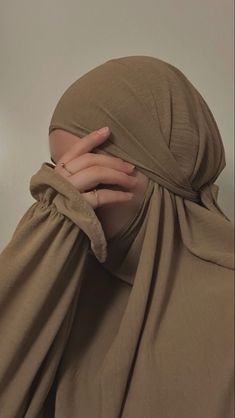 a woman wearing a brown hijab covering her face