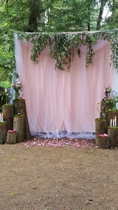 an outdoor wedding setup with pink drapes and flowers on the wall, surrounded by candles