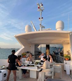 people are sitting at a table on the deck of a boat in the open water