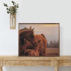 an oil painting of horses and foals on a shelf next to a vase with flowers