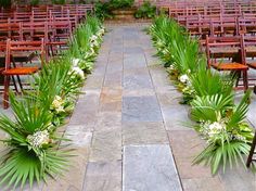 rows of wooden chairs lined up with flowers and greenery on the floor in front of them