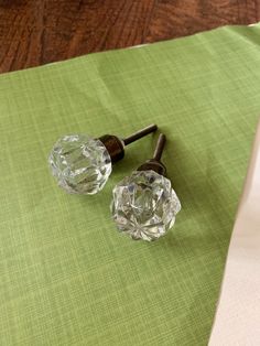 two glass knobs sitting on top of a green table cloth next to each other