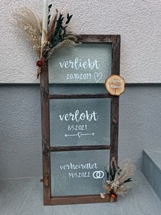 a wooden sign that has some writing on it and two candles in front of it