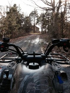 an atv driving down a dirt road in the woods