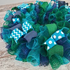 a green and blue wreath with white polka dots on the top is sitting on a wooden table