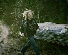 a woman walking down a dirt road in the woods