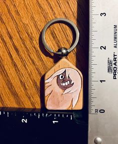 a wooden keychain with a cartoon character on it and a ruler next to it