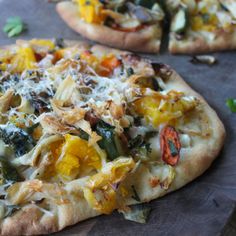 two pizzas with different toppings sitting on a cutting board