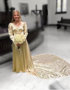 a woman in a wedding dress standing next to a large white flower bouquet on the floor