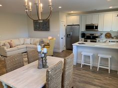 a living room filled with furniture next to a kitchen and dining room table in front of a stove top oven