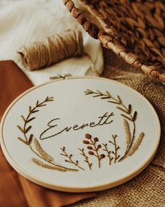 a close up of a embroidery on a table with a basket and yarn in the background