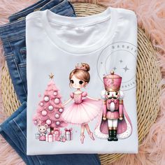 a t - shirt with a nutcracker and a girl in a pink dress next to a christmas tree