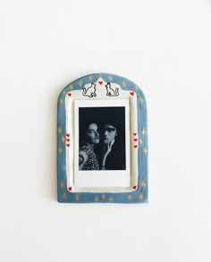 an old photo frame with two people in it on a white wall next to a clock