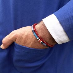 The HORACE men's bracelet elegantly combines natural orange Carnelian stone beads (4mm in size) with a handwoven weave of contemporary blue linen threads. These elements seamlessly merge, held together by a brushed stainless steel interlocking clasp, providing a perfect balance between strength and refinement. HORACE delicately reimagines the male ethnic jewel with finesse and color, embodying for the wearer the bold affirmation of their uniqueness. The HORACE model is available in 5 different c Modern Handmade Blue Beaded Bracelets, Modern Blue Handmade Beaded Bracelets, Modern Beaded Bracelets With Natural Stones For Gift, Handmade Modern Blue Beaded Bracelets, Modern Blue Beaded Bracelets As Gift, Modern Blue Beaded Bracelets For Gift, Modern Gemstone Beaded Bracelets For Gift, Modern Gemstone Beaded Bracelets As Gift, Carnelian Bracelet Men