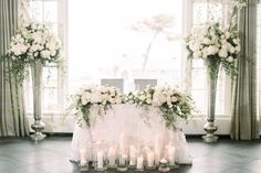 a table topped with lots of white flowers and candles