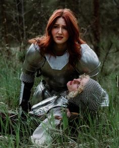 a woman with red hair sitting next to a man in armor