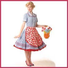 a woman in a red and white checkered dress holding a basket with flowers on it