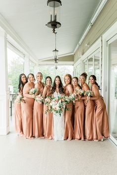 a group of women standing next to each other in front of a building holding bouquets