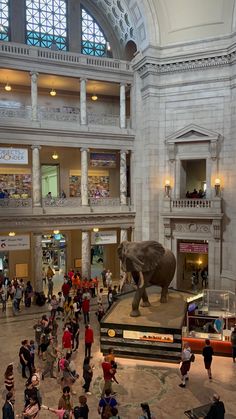 an elephant statue in the middle of a building with people walking around and looking at it