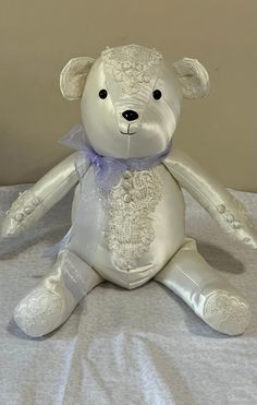 a white teddy bear sitting on top of a bed