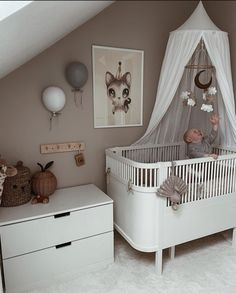 a baby in a white crib next to a dresser and pictures on the wall