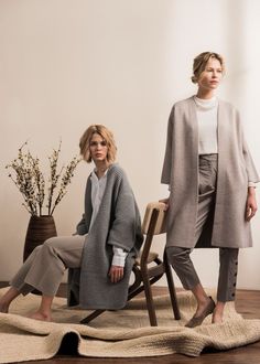 two women sitting on chairs in the middle of a room, one with her legs crossed