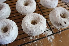 doughnuts are cooling on a wire rack with powdered sugar sprinkles