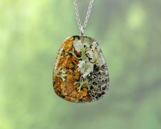 Celebrate the beauty of the natural world with this stunning botanical pendant necklace, featuring real lichen 🍃 and preserved moss 🌿 encapsulated in clear resin. This botanical resin jewelry captures the essence of the forest, offering a unique and elegant piece that brings nature's wonders into your everyday style. The modern geometric design adds a contemporary twist to the natural elements, making it perfect for those who love a combination of organic and minimalist aesthetics. This terrarium necklace is ideal for nature lovers who want to carry a little piece of the forest with them. 🍄 Our Botanical Jewelry: https://www.etsy.com/es/shop/NatureResinJewelry?section_id=51200953 💚 Handmade with love and care 💚 ADDITIONAL INFORMATION 🎁 This unique nature necklace comes carefully pack Nature-inspired Pendant Necklace For Healing, Nature-inspired Necklaces With Pressed Flowers, Nature-inspired Necklace With Large Oval Pendant, Nature-inspired Amber Pendant Necklace, Nature-inspired Green Necklace With Large Pendant, Sterling Silver Nature-inspired Necklace With Natural Inclusions, Amber Resin Pendant Necklace, Nature-inspired Resin Necklaces With Round Pendant, Nature-inspired Resin Necklace With Round Pendant