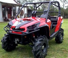 a red and black utility vehicle parked on top of a grass covered field in front of a house