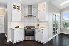 a kitchen with white cabinets and stainless steel appliances in the middle of an open floor plan