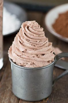 a cup filled with chocolate frosting on top of a wooden table