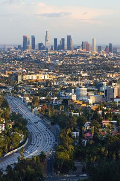 an aerial view of a city with lots of traffic and tall buildings in the background