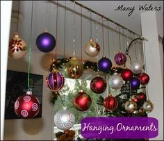 christmas ornaments hanging from the ceiling in front of a window with purple and red balls