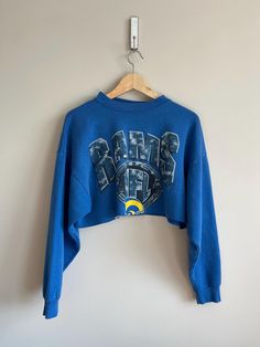 2000 vintage super trendy LA Rams NFL football sweatshirt cropped  authentic vintage crewneck  You will be the only one who has this trendy LA rams vintage sweatshirt :) vintage wear and character as pictured  no pilling great vintage condition very soft Size medium cropped it fits super cute model is 5'5 normally wears a size small Sporty Cropped Sweater For Fall Streetwear, Sporty Cropped Sweater For Streetwear In Fall, Throwback Fan Gear Tops For Fall, 90s Style Long Sleeve Tops For Game Day, Oversized Throwback Top For Fall, 90s Style Sweatshirt For Fall Sports Events, Blue Tops For Football Season Streetwear, Oversized Throwback Fall Tops, Oversized Sporty Cropped Sweater For Streetwear