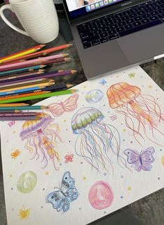 a laptop computer sitting on top of a desk next to colored pencils